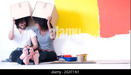 Glückliche junge multiethnischen paar entspannen und spielen mit Kartons nach einen Raum in ihrem neuen Haus auf dem Boden zu malen Stockfoto