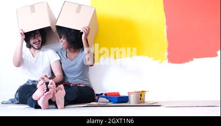 Glückliche junge multiethnischen paar entspannen und spielen mit Kartons nach einen Raum in ihrem neuen Haus auf dem Boden zu malen Stockfoto