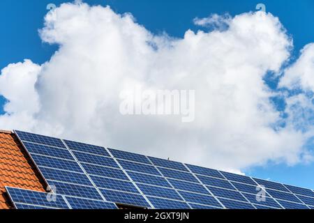 Sonnenkollektoren und Solaranlage Photovoltaik auf dem Dach eines Privathauses und dem weiß-blauen bayerischen Himmel Stockfoto