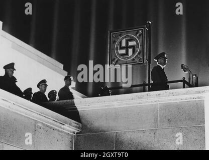 Hitler und ein Hakenkreuz-Standard mit der beeindruckenden Lichtkathedrale, entworfen von Albert Speer, bei der NSDAP-Kundgebung in Nürnberg Stockfoto