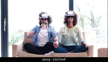 Multiethnische paar mit virtual-Reality-Kopfhörer im Wohnzimmer zu Hause Menschen spielen mit neuen Trends-Technologie Stockfoto