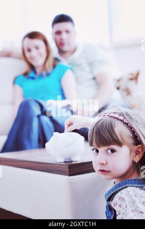 junge Elternteil zu Hause mit schönen Kind Einsparungen vornehmen und Münzen Geld im Sparschwein Stockfoto