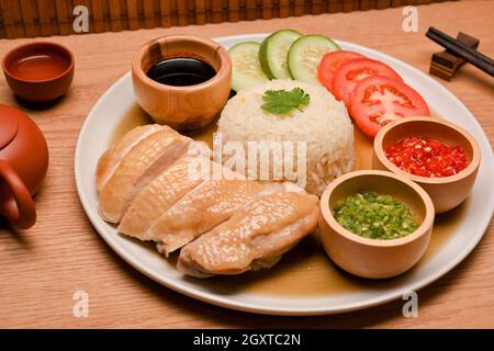 Bild von saftigem Hühnerreis aus Hainanese mit speziellem Chili und süßen Sojabohnensaucen und frischen Gemüsegerichten. Asiatisches Speisekonzept Stockfoto