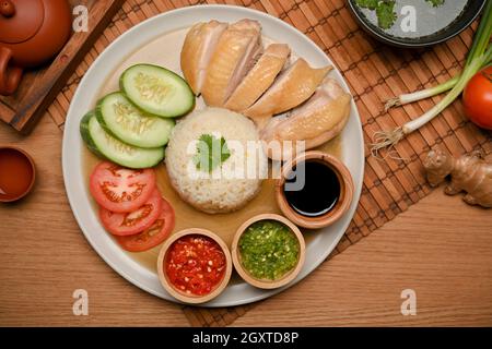 Hainanesischer Hühnerreis oder gedämpftes Huhn mit gewürztem Reis mit Chilisaucen und süßer Sojasauce Stockfoto