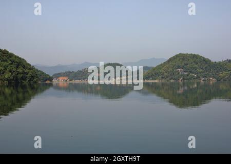 Morgen Szene an begnas See, Nepal. Hügel bedeckt von Wald Spiegelung im Wasser, Ansicht von Majhjkuna. Landschaft in der Nähe von Pokhara. Stockfoto