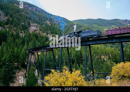 Zug Lokomotive auf große Metallbrücke in Berge von Pinien bedeckt Stockfoto