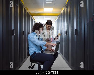 Team von jungen Technikern zusammen, die auf Servern im Rechenzentrum mit Laptop Stockfoto