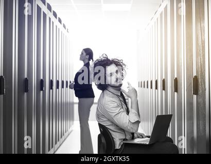 Team von jungen Technikern zusammen, die auf Servern im Rechenzentrum mit Laptop Stockfoto