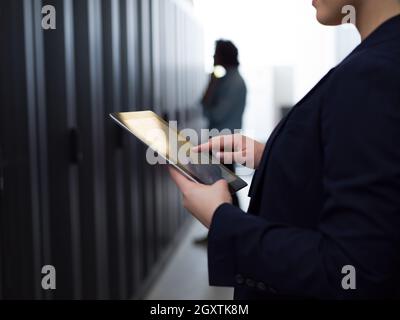 Weibliche IT-Engineer, der an einen Tablet-PC im Serverraum an modernen Data Center Stockfoto