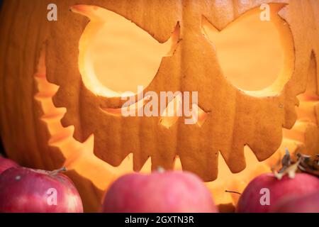 Großer Kürbis mit leuchtenden Augen und Mund in Äpfeln, Nahaufnahme. Konzept der teuflischen Atmosphäre von Halloween Stockfoto