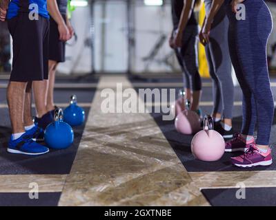 Eine Gruppe gesunder junger Sportler, die im Fitnessstudio Übungen mit Kettlebells machen Stockfoto