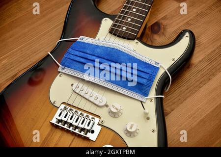 Schützende chirurgische Gesichtsmaske, die ein Elektrikgitarren-Symbol für Schweigen umhüllt Kreative während der Corona-Virus-Krankheit Pandemieausbruch vertikales Bild wo Stockfoto