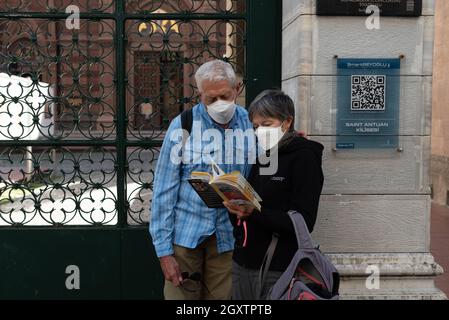 Istanbul, Türkei. 5. Oktober 2021 ausländische Touristen, die Schutzmasken tragen, lesen vor der Kirche St. Antuan, Istiklal Street, Taksim, I, einen Reiseführer Stockfoto