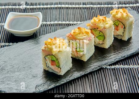 Köstliche gebackene Brötchen mit Käse, Huhn, Tomaten, Kohl auf einem Steinständer, Sushi Stockfoto