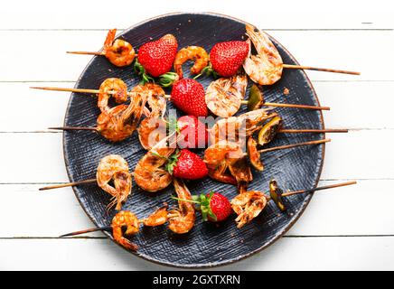 Appetitlich gegrillte Garnelen auf Holzspießen mit Erdbeeren.Garnelen bbq Stockfoto