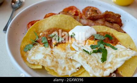 Frühstück Hard Shell Tacos und Bacon Tomaten und Eier am Morgen Mahlzeit auf einem Teller Stockfoto