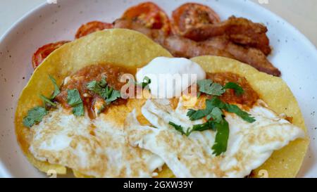 Frühstück Hard Shell Tacos und Bacon Tomaten und Eier am Morgen Mahlzeit auf einem Teller Stockfoto