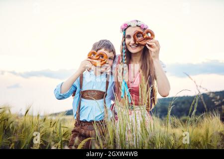 Mutter und Sohn in Bayern schauen durch Brezeln auf die Kamera Stockfoto