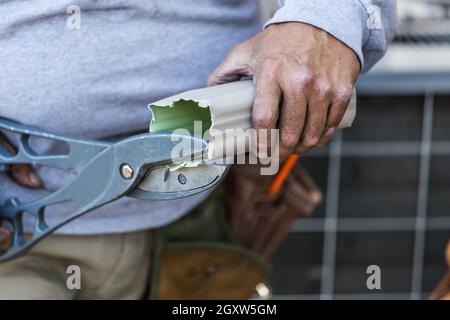 Arbeiter Schneidet Aluminium-Regenrinne Mit Schweren Scheren. Stockfoto