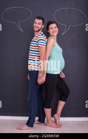 Junge schwangere paar Gedanken über Namen für Ihr ungeborenes Baby und sie schreiben auf eine Schwarze Schiefertafel Stockfoto
