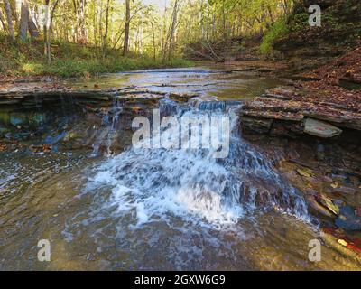 Wasserfall über flachen Felsen im Herbstwald Stockfoto