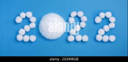 Frohes neues Jahr 2022 Feier. Schneeweiße Weihnachtskugeln, Schnee, 2022 kreative Zahl auf hellblauem Hintergrund. Flach liegend. Banner Stockfoto
