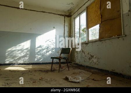 Alter Stuhl in der Ecke eines schmutzigen Zimmers Stockfoto