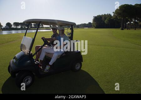 Golf-Spieler fahren Wagen mit Kurs auf schönen Morgen Sonnenaufgang. Freunden zusammen Spaß und Entspannung im Urlaub. Stockfoto