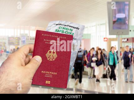 Hand mit einem deutschen Pass und einem faltigen Coronavirus Covid 19-Immunitätszertifikat aus Papier. Verschwommener Flughafen im Hintergrund. Immunität gegen Covi Stockfoto
