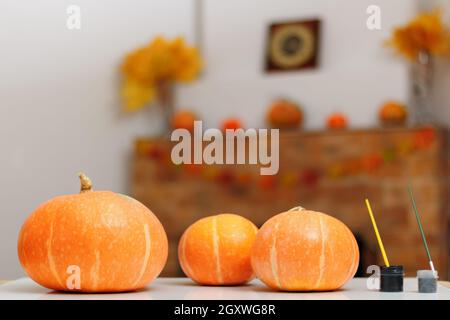 Vorbereitung auf Halloween. Kürbisse auf dem Tisch vor dem Hintergrund eines rustikalen Kamins mit Herbstdekorationen. Stockfoto