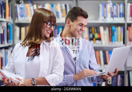 Zwei Schüler mit moderner Technik stehen in der Schulbibliothek Stockfoto