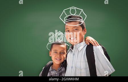 Junge Hispanic Student Boy tragen Rucksack vor der Tafel mit Feuerwehrmann Helm und Polizist hat gezeichnet mit Kreide über die Köpfe. Stockfoto