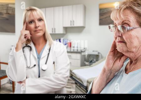 Einfühlsame Arzt Hinter Gestörte ältere Erwachsene Frau im Amt. Stockfoto