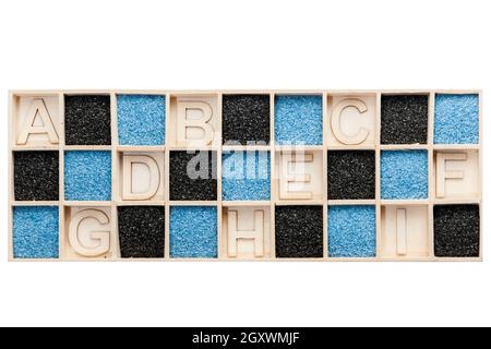 Rechteckige Holzkiste mit quadratischen Fächer teilweise mit blauen oder schwarzen Dekolack Sand gefüllt sowie mit dem Buchstaben A bis I in das leere Feld Stockfoto