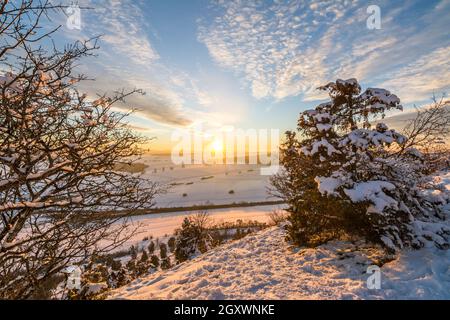 Schöner, farbenfroher Sonnenuntergang über der Winterlandschaft in den Schwäbischen Alpen mit Bäumen im Vordergrund Stockfoto