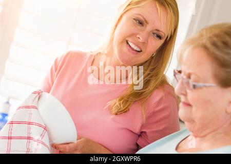 Ältere Erwachsene Frau und Tochter sprechen am Waschbecken in der Küche. Stockfoto