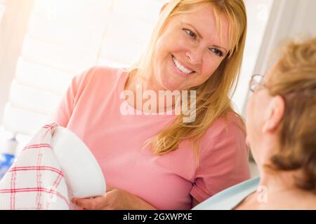 Ältere Erwachsene Frau und Tochter sprechen am Waschbecken in der Küche. Stockfoto