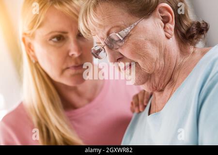 Junge Frau tröstet traurige Senior Erwachsenfrau. Stockfoto