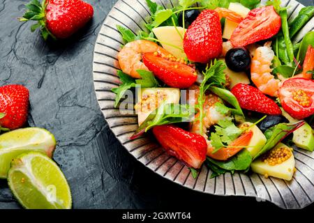 Diätsalat mit Garnelen, Erdbeeren, Avocado und Grün. Gesunder Salat aus stilvollem Metall Platte Stockfoto