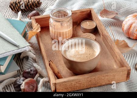 Hygge Stillleben mit einer Tasse Kaffee und Duftkerzen auf einer warmen Decke, gemütliche drinnen Szene Stockfoto