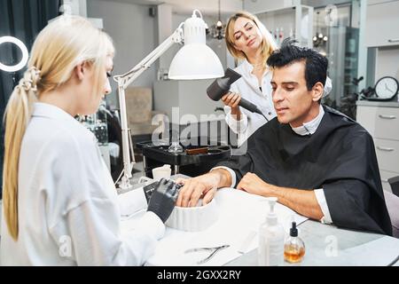 Männlich auf Maniküre bekommt seine Haare im Schönheitssalon getrocknet Stockfoto