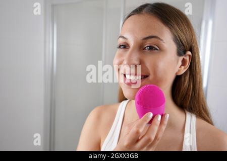 Nahaufnahme von lächelnden Mädchen Reinigung der Haut mit Silikonbürste Ultraschall im Badezimmer Stockfoto