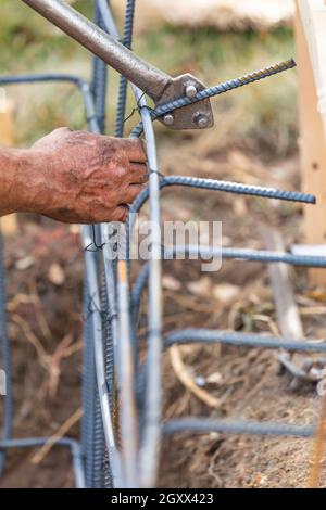 Arbeitnehmer mit Hilfe der Werkzeuge zu verbiegen Beton-rippenstahl an der Baustelle. Stockfoto