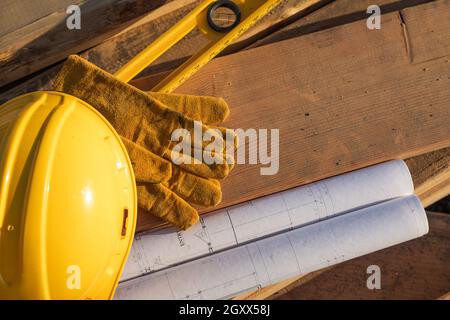 Zusammenfassung von Constrcution Schutzhelm, Handschuhe, Ebene und Haus Pläne ruhen auf Holzplanken. Stockfoto