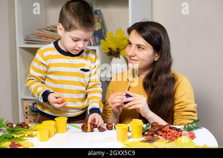 Mutter und Sohn Formen herbstliche Raupe aus Kastanien und Plastilin. Stockfoto