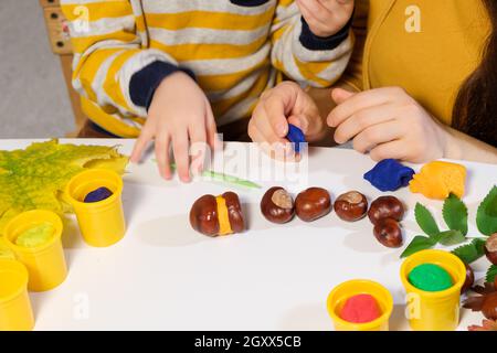 Mutter und Sohn Formen herbstliche Raupe aus Kastanien und Plastilin. Stockfoto