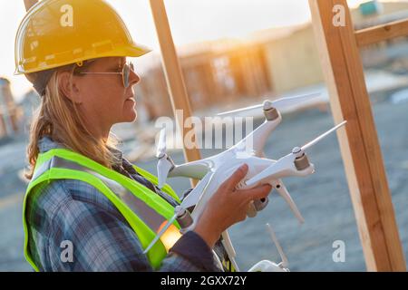 Weibliche Unmanned Aircraft Systems (UAS) Quadcopter Drone Pilot Holding Drohne an der Baustelle. Stockfoto