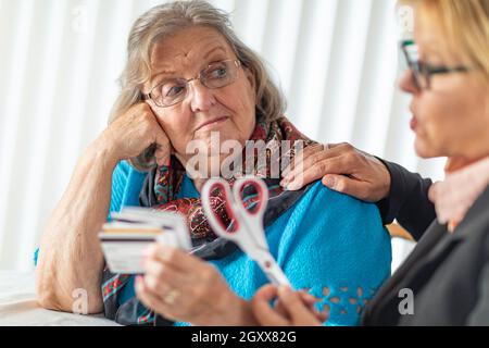 Finanzielle Berater Übergabe Schere zu den älteren Dame Holding Kreditkarten. Stockfoto