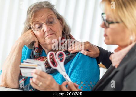 Finanzielle Berater Übergabe Schere zu den älteren Dame Holding Kreditkarten. Stockfoto