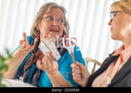 Finanzielle Berater Übergabe Schere zu den älteren Dame Holding Kreditkarten. Stockfoto